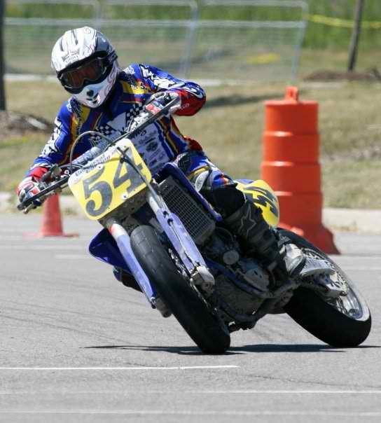 Young Michael leaning his #54 supermoto bike through a turn on pavement, before 2005