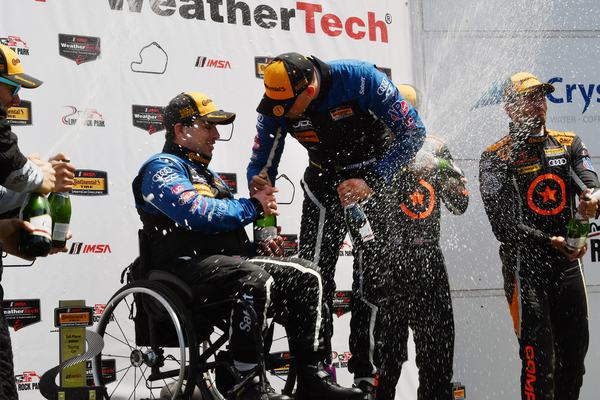 Champagne spray on the podium with Michael in his wheelchair, 2018