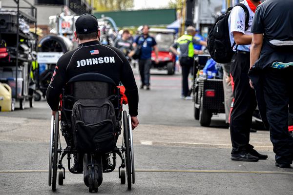 Michael rolling through the paddock in his wheelchair, JOHNSON across his back, 2021