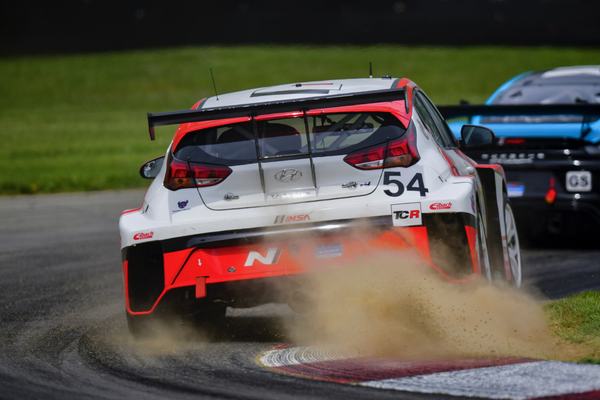 The #54 Hyundai kicking up dirt over a curb, 2021