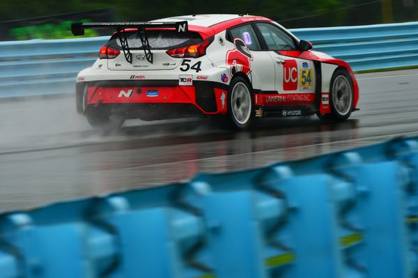 The #54 Hyundai throwing spray on a wet track, 2021