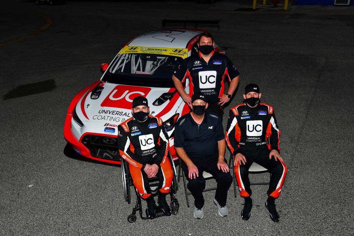 Michael in his wheelchair with the Michael Johnson Racing and Bryan Herta Autosport crew in front of the #54 Hyundai at night